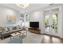 Bright living room with hardwood floors, gray sofa, and natural light from the French doors at 710 Independence Pl # 103, Raleigh, NC 27603