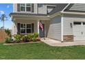 Inviting front porch with an American flag, beautiful landscaping and well-manicured lawn at 784 Cypress Rd, Cameron, NC 28326