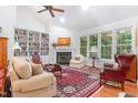 Sunlit living room features hardwood floors, a cozy fireplace, and large windows with backyard views, perfect for relaxation at 850 N Langdon, Pittsboro, NC 27312