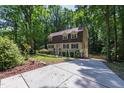 Two story home with a long driveway and mature trees and shrubs at 1005 Temple St, Raleigh, NC 27609