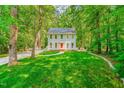 Beautifully landscaped front yard with a charming two-story home nestled among mature trees at 114 Bonaparte Dr, Hillsborough, NC 27278