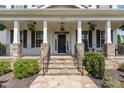 Inviting front porch with stone pillars, hanging plants, and a decorative black door at 1304 Revolution Cir, Raleigh, NC 27603