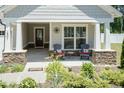 Inviting front porch with stone accents, seating, and a decorative door for a cozy welcome at 2501 Impulsion Dr, New Hill, NC 27562