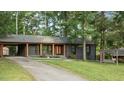 Charming, single-story home with dark exterior paint, bright trim, a level lawn and mature shade trees at 307 Yowland Rd, Henderson, NC 27536
