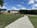 Community playground featuring modern equipment, walking path, and ample green space at 3124 Mackinac Island Ln, Raleigh, NC 27610