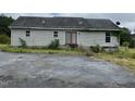 Rear view of a house showing siding, small windows, and a rear door with a dilapidated paved parking area at 3213 Sam Usry Rd, Oxford, NC 27565