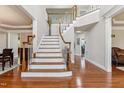 Grand foyer showcasing a staircase with wood banister and gleaming hardwood floors at 3404 Mount Pisgah Way, Cary, NC 27519