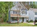 Charming two-story home with light blue siding, black shutters, front porch, and landscaped yard at 4520 Timberhurst Dr, Raleigh, NC 27612