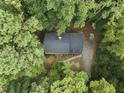 Stunning aerial view of a wooded property featuring a home with a dark roof, nestled among lush green trees at 5125 Penny Rd, Raleigh, NC 27606