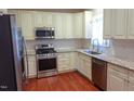 Modern kitchen featuring stainless steel appliances, granite countertops, white cabinets, and beautiful hardwood floors at 5917 Clearsprings Dr, Wake Forest, NC 27587