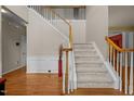 Bright foyer with hardwood floors, staircase with white railings, and decorative wainscoting at 708 Cheselden Dr, Durham, NC 27713