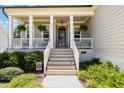 Inviting front porch featuring hanging plants, a cozy seating area, and a stylish welcome mat at 816 Trumpet Vine Ct, Wendell, NC 27591