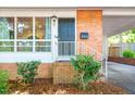 Close-up of the front door with brick facade, small bushes, and a covered parking area at 903 W Maynard Ave, Durham, NC 27704