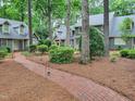 Well-maintained home exterior with a brick pathway lined with trees, connecting multiple units and enhancing curb appeal at 107 Long Shadow Ln, Cary, NC 27518