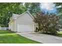 Side view of a two-car garage with white door and neutral siding, nestled in a well-kept yard at 1102 Laurens Way, Knightdale, NC 27545