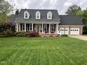 Charming brick home featuring a well-manicured lawn, a two-car garage and a welcoming covered front porch at 114 Fieldstone Dr, Burlington, NC 27215