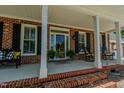 Inviting front porch area with brick steps, white columns, rocking chairs, and fresh potted plants at 114 Fieldstone Dr, Burlington, NC 27215