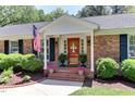 Welcoming front porch with a bright red door, lush greenery, and charming potted plants at 1206 Ivy Ln, Raleigh, NC 27609
