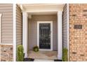 Close-up of front door with black door, brick and siding accents, and house number 1230 at 1230 Adrian Ct, Mebane, NC 27302