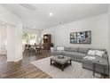 Bright living room with sleek hardwood floors, grey sofa, and natural light from the window at 1230 Adrian Ct, Mebane, NC 27302