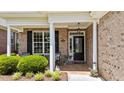 Inviting front porch with brick facade, white columns, black door, and decorative details under a bright covered entryway at 232 Shady Hollow Ln, Garner, NC 27529