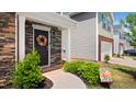 Inviting front porch with a decorative wreath, stone accents, and manicured landscaping at 2406 Lily Dr, Haw River, NC 27258