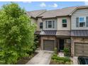 Townhome showcasing stone facade, garage, green front door, landscaping, and neutral siding at 256 Rubrum Dr, Hillsborough, NC 27278