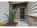 Close-up of the front door, showcasing stone facade and green door and a small garden at 256 Rubrum Dr, Hillsborough, NC 27278
