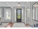 Bright foyer with hardwood floors, a stylish light fixture, and a view of the front yard through the glass-paneled front door at 2711 Jordan Pointe Blvd, New Hill, NC 27562