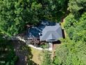 Aerial view of a home with a dark roof, surrounded by lush, mature trees in a private backyard setting at 5304 W Oaks Dr, Fuquay Varina, NC 27526