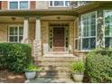 Elegant front entrance with stone pillars, a wood door, and decorative planters at 5520 Creek Pine Dr, Wake Forest, NC 27587