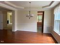 Bright dining room with hardwood floors, decorative chandelier, and views into the living spaces at 5804 Claribel Ct, Raleigh, NC 27612
