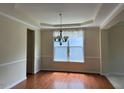Dining room features hardwood floors, a tray ceiling, and a window with natural light at 5804 Claribel Ct, Raleigh, NC 27612
