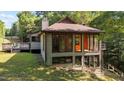 View of a multi-level house with a deck, large windows, and wood siding, nestled in a verdant landscape at 5900 Ebenezer Church Rd, Raleigh, NC 27612