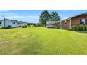 Expansive backyard with lush green lawn, mature trees, and accessory buildings on a sunny day at 6080 Us 421 N, Lillington, NC 27546