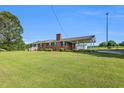 Traditional brick home with a large front yard, covered parking, and mature trees on a sunny day at 6080 Us 421 N, Lillington, NC 27546