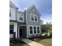 Close up of a two-story townhome exterior with gray siding, stone accents and landscaping at 6451 Granite Quarry Dr, Raleigh, NC 27610