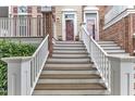 Close up view of wooden and white stairways leading to front door, accented by plants, flower wreaths, and brick features at 9211 Calabria Dr # 104, Raleigh, NC 27617