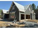New construction home featuring gray vertical siding, white trim, and ladders. Includes a two-car garage at 93 Bur Oak Ct, Pittsboro, NC 27312