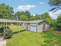 A detached garage and carport sit among well-manicured lawns and mature trees at 102 Pine St, Dunn, NC 28334