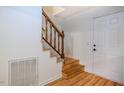 Bright entryway featuring hardwood floors, a staircase with wooden banister, and a white front door at 106 Redbud, Pittsboro, NC 27312