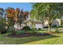 Landscaped front yard with mature trees leading to a charming two-story home with stone accents at 109 Faldo Cv, Raleigh, NC 27603