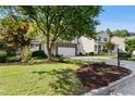 Inviting front yard with lush landscaping leading to a two-story home with stone facade and a driveway at 109 Faldo Cv, Raleigh, NC 27603