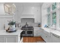 Bright white kitchen with a large center island, Wolf range, and farmhouse sink at 1305 Queensferry Rd, Cary, NC 27511