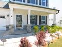 Charming home featuring a covered front porch with stone accents, complemented by manicured landscaping at 1311 Arena Ln, Fuquay Varina, NC 27526