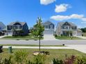 A street view showcasing well-maintained homes with manicured lawns and mature trees on a sunny day at 1311 Arena Ln, Fuquay Varina, NC 27526
