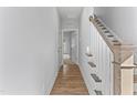 Inviting hallway with hardwood floors leading to a staircase with wooden handrail and white balusters at 1900 Fishamble St # 17, Fuquay Varina, NC 27526