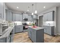 Well-lit kitchen with stainless steel appliances, gray cabinetry, granite countertops, and a kitchen island at 24 W Catalina Ct, Clayton, NC 27527