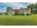 Charming home with a well-manicured lawn and inviting red umbrellas, ideal for outdoor enjoyment at 2646 Laurel Mill-Centerville Rd, Louisburg, NC 27549
