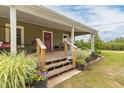 Inviting front porch featuring beautiful flowerpots and a red door, perfect for relaxing outdoors at 2646 Laurel Mill-Centerville Rd, Louisburg, NC 27549
